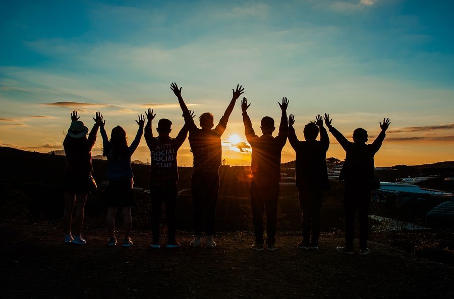 Group of teenagers arms raised in the sunset