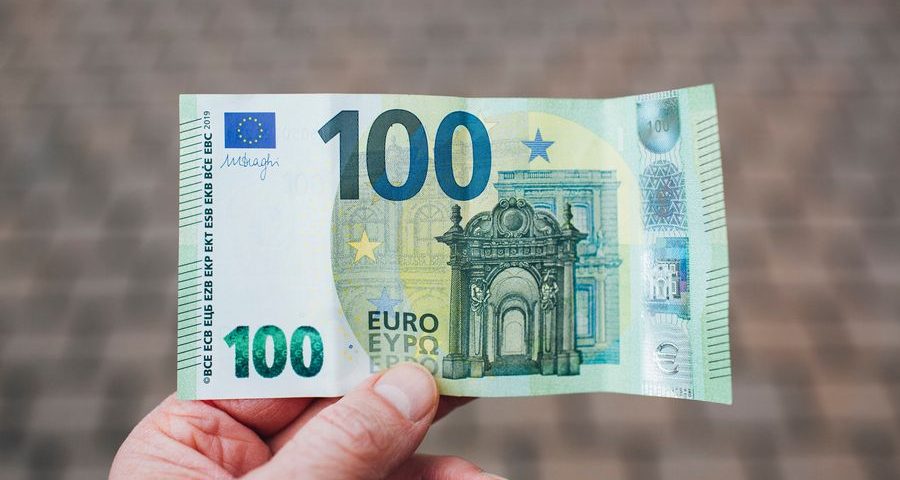 A hand offers a 100 euro note