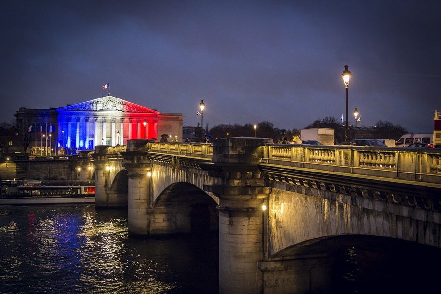 Paris at night with the French flag illuminated on a building