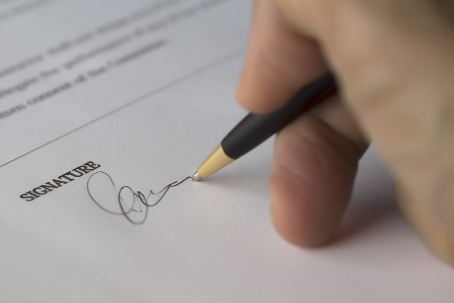 A close up of a hand signing a document. By Pixabay on Pexels