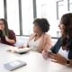 Three women of colour talk in a meeting room. By Christina Morillo on Pexels