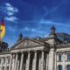 German parliament building against a blue sky, with a german flag. By by Felix-Mittermeier.de from Pixabay