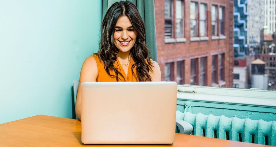 A woman smiles as she watches something on her laptop. Photo by Jopwell on Pexels