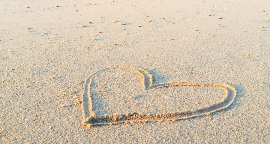 A heart drawn in the sand on a beach. Photo by Khadeeja Yasser on Unsplash