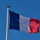 The French flag flies against a clear blue sky. By Rafael Garcin on Unsplash