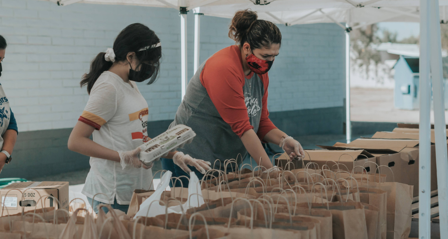 People fill bags with donated food. By Ismael Paramo on Unsplash