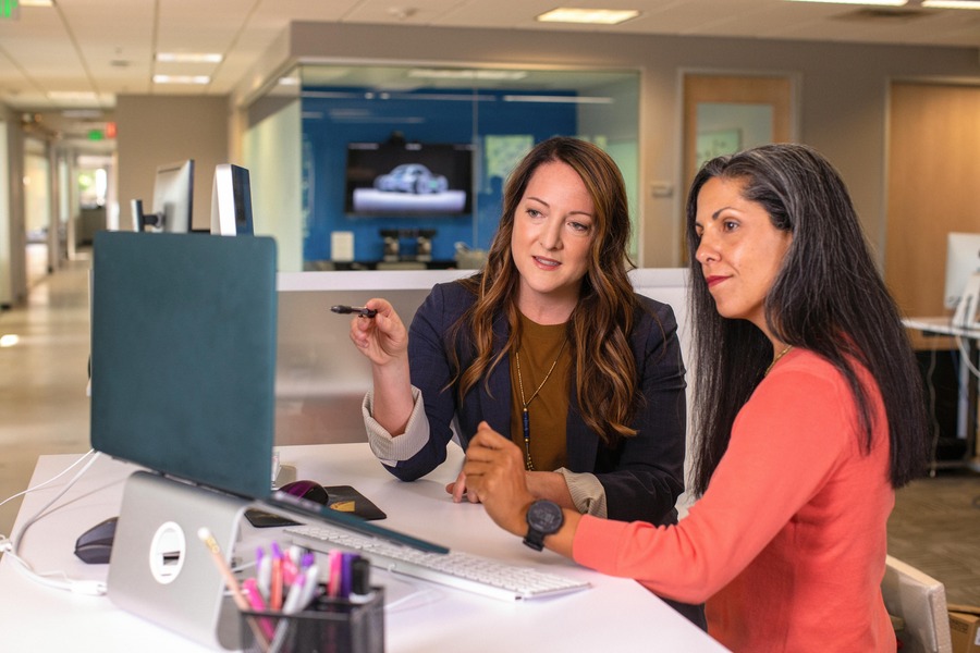 two women at a computer in an office. One is explaining something to the other one. By LinkedIn Sales Navigator on Pexels