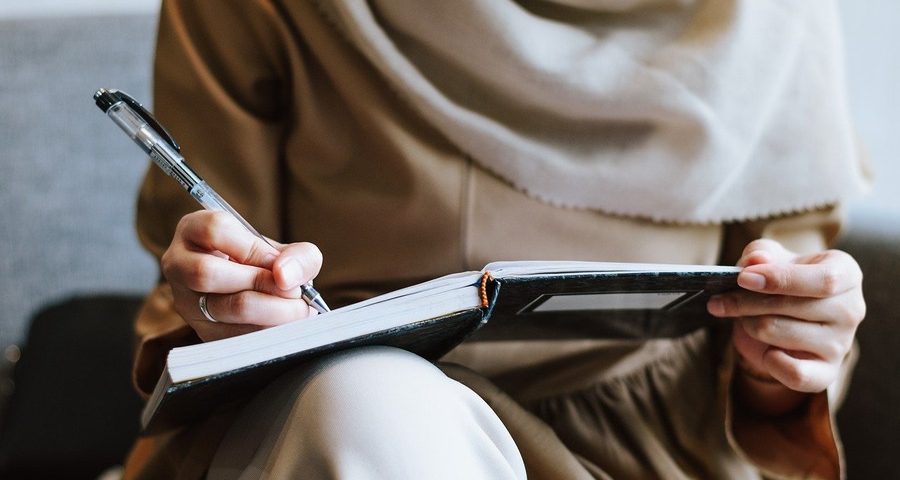 A woman who could be Muslim writing notes. By IqbalStock on pixabay