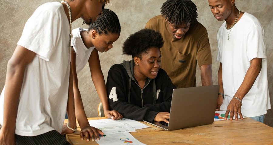 A group of young people of colour gathered around a laptop. By Monstera Production on Pexels
