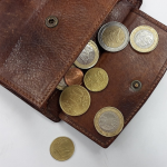 A open wallet with euro coins spilling out of it. By Cocoparisienne on pixabay
