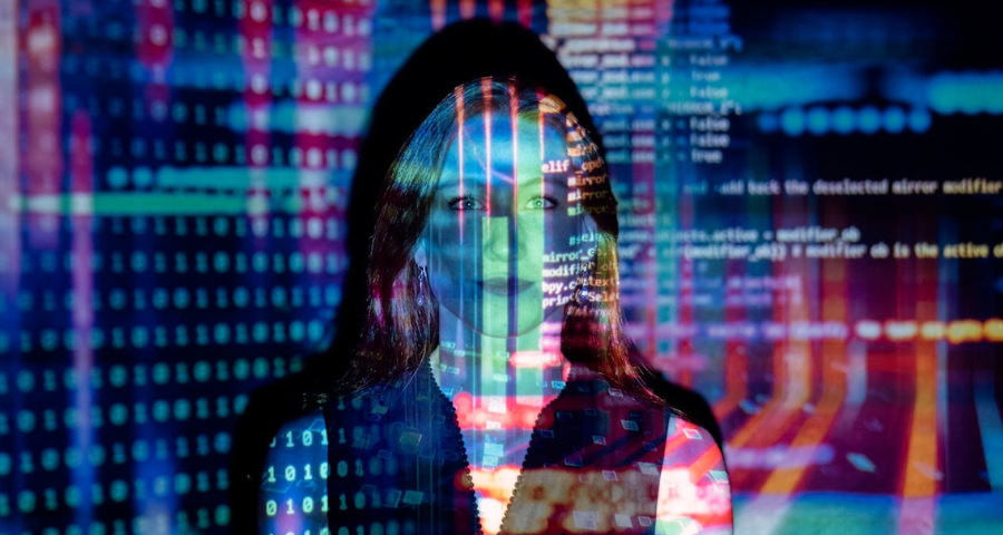 An image denoting AI: a woman standing with an image of numbers and symbols transposed onto her. By ThisIsEngineering via Pexels