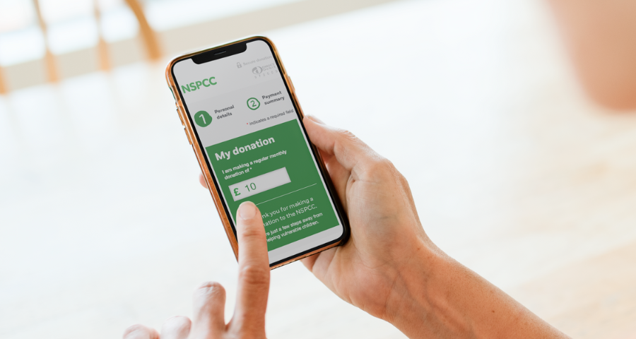 A hand poised over a NSPCC donate screen on a mobile