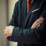 A man in a sharp suit, standing with his arms folded. By Andriyko Podilnyk on unsplash