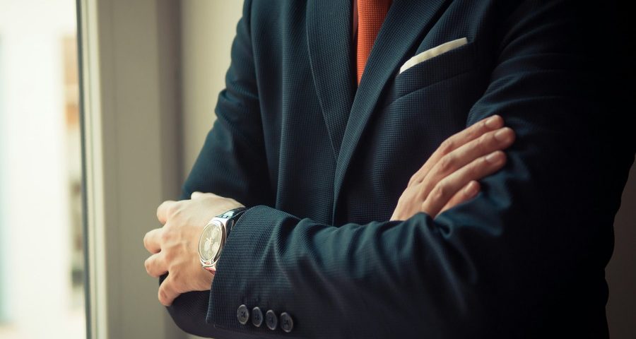 A man in a sharp suit, standing with his arms folded. By Andriyko Podilnyk on unsplash