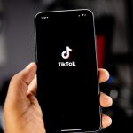 A hand holds up a phone showing the tiktok icon. by Solen Feyissa on Unsplash