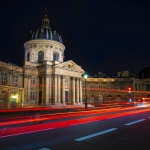 Red lights speeding past a historic building.By Céline Martin from Pixabay