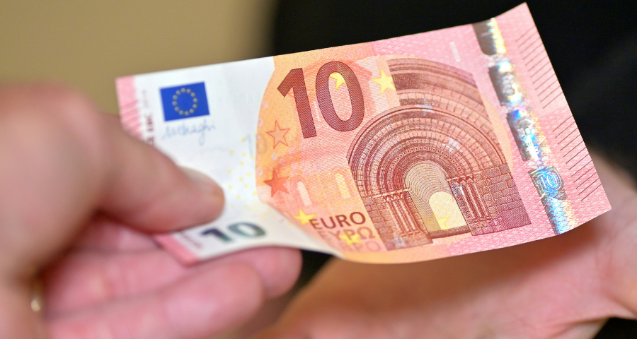 A hand giving a 10 euro note to another person. By Andres Siimon on unsplash