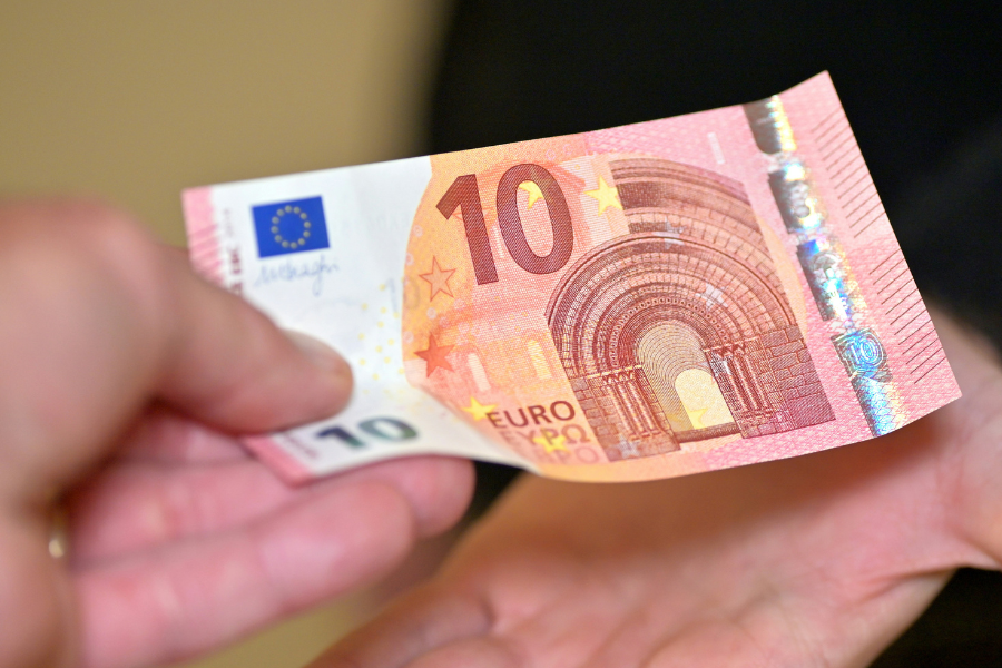 A hand giving a 10 euro note to another person. By Andres Siimon on unsplash