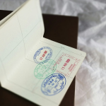 An open passport showing different country stamps. By Global Residence Index via Unsplash.