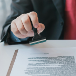 A man in a suit stamps a document. By Getty Images for Unsplash+
