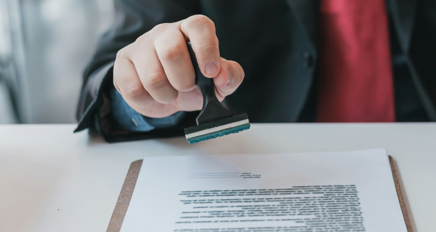 A man in a suit stamps a document. By Getty Images for Unsplash+
