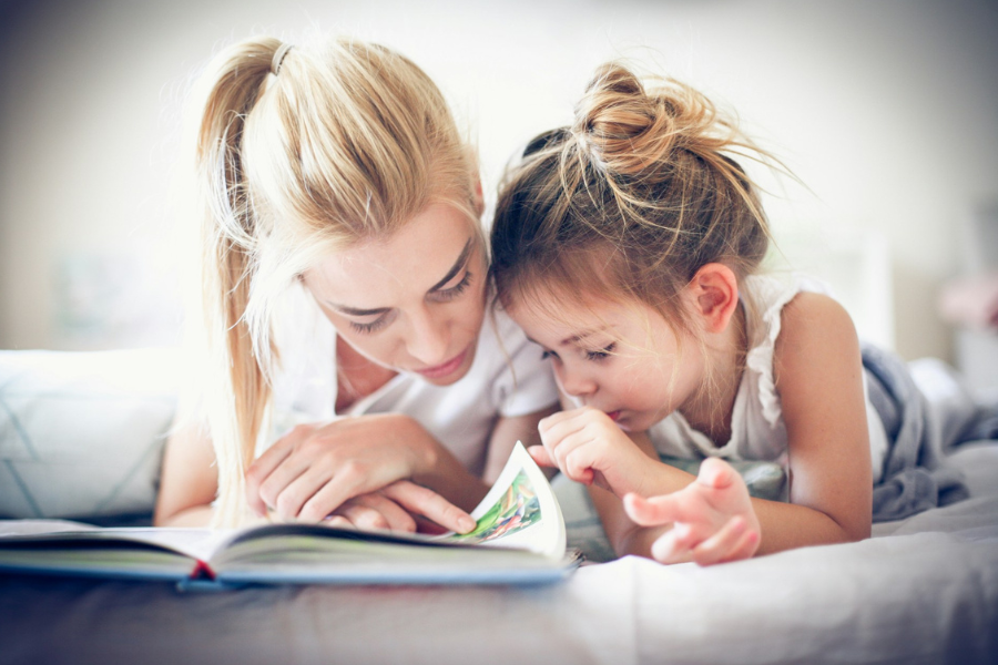 A mother reading with her young daughter. By Getty Images for Unsplash+