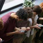 Looking down at a row of young adults all looking at their phones. By Fauxels on Pexels