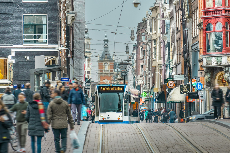 A street scene in the Netherlands with people, a tram and shops