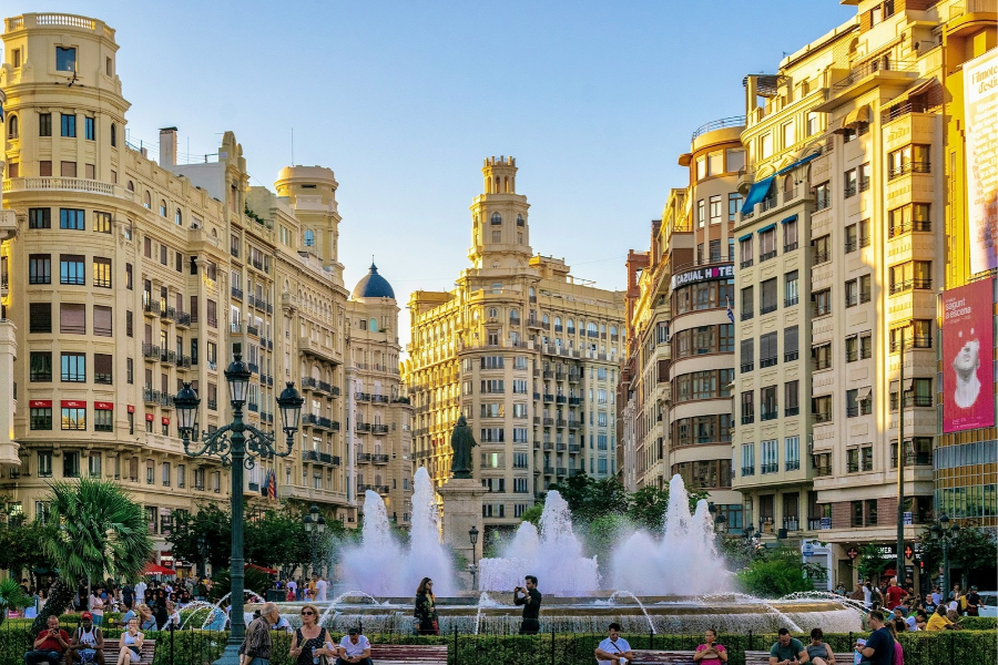 A group of people standing around a big fountain in Valencia Spain